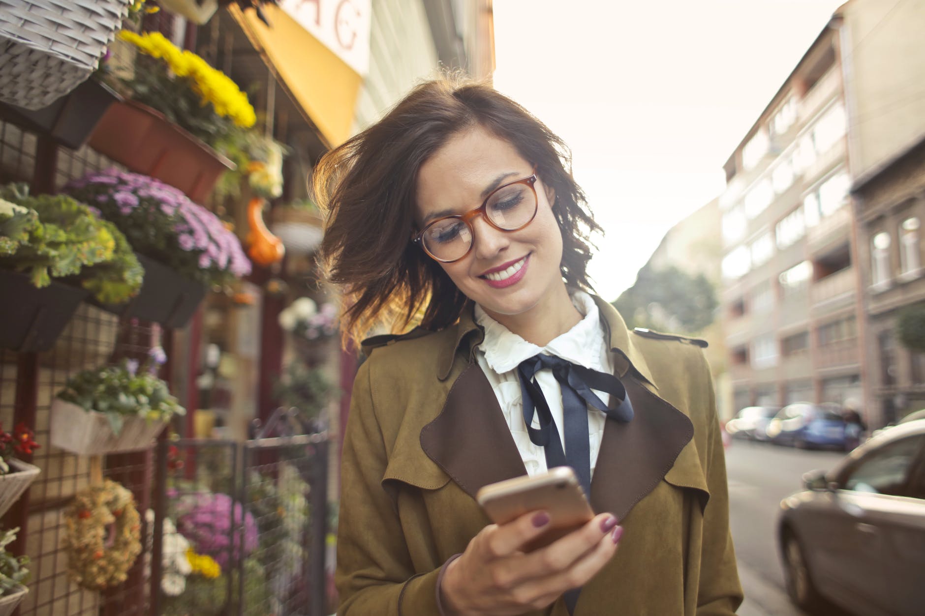 woman beside flower shop using smartphone